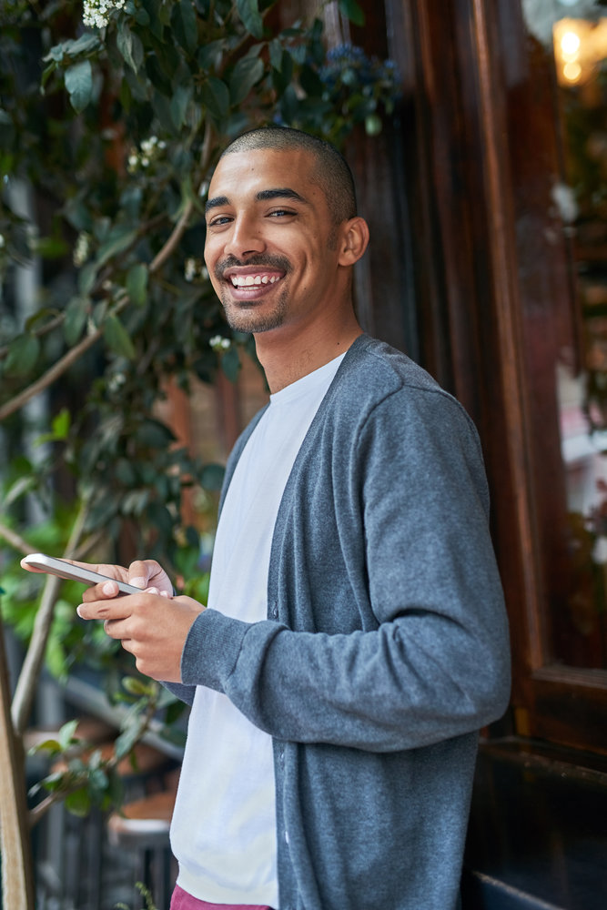 Portrait of a young man texting on his cellphone outside.