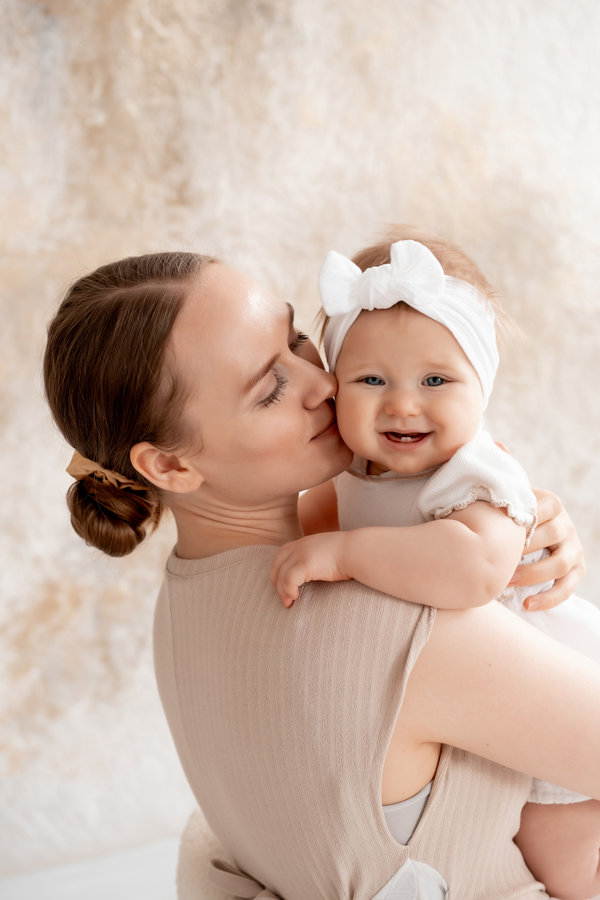 mom and baby, mother gently hugs her baby, kissing him at home, motherhood and caring.
