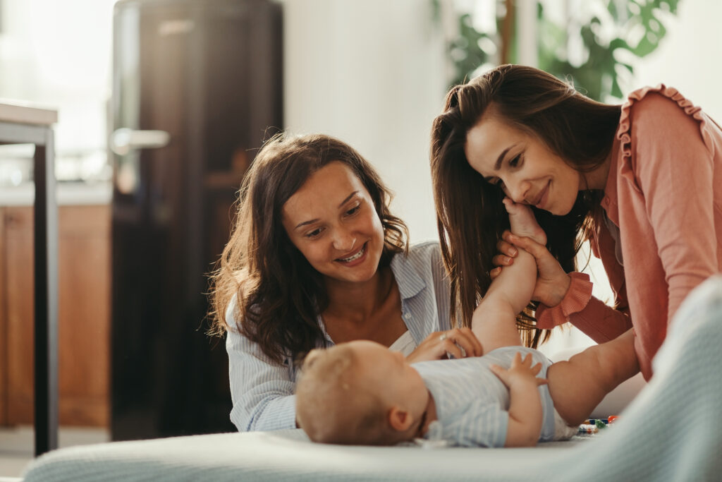 Loving lesbian caouple playing with their baby while spending time together at home.