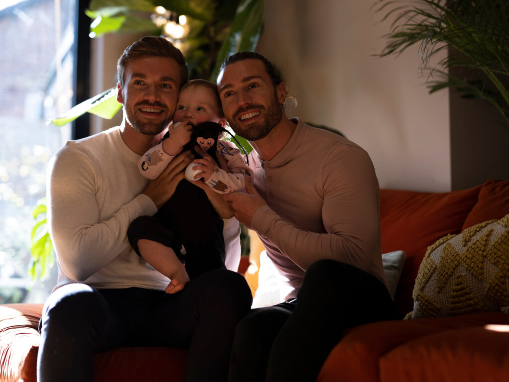 Portrait of gay couple with baby daughter in living room
