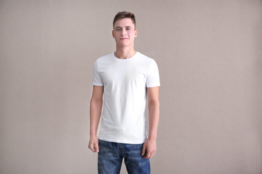 Young man in color t-shirt on light background. Mockup for design