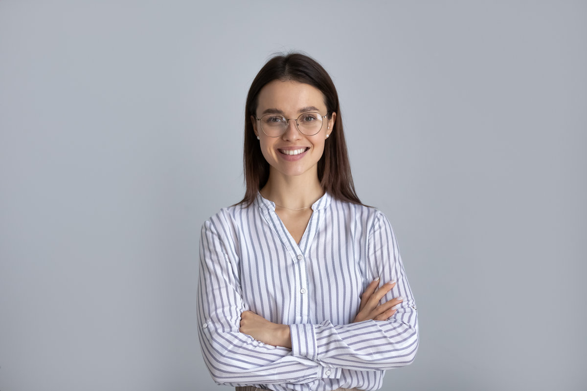Happy millennial business woman in glasses posing with hands folded isolated on white, looking at camera, smiling. Confident female customer, young student girl, professional head shot portrait