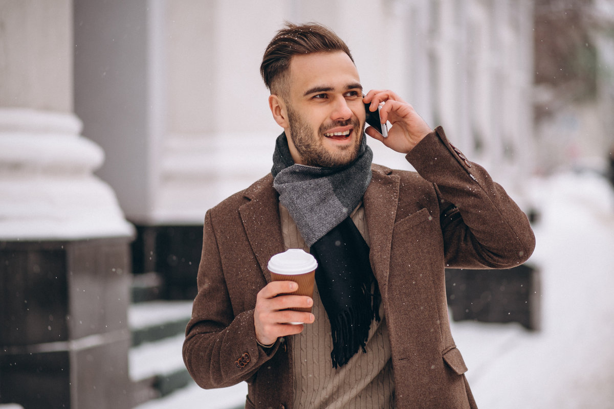 Young handsome man drinking coffee and talking on phone
