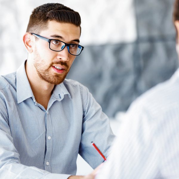 Two handsome businessman in office sitting at desk and talking