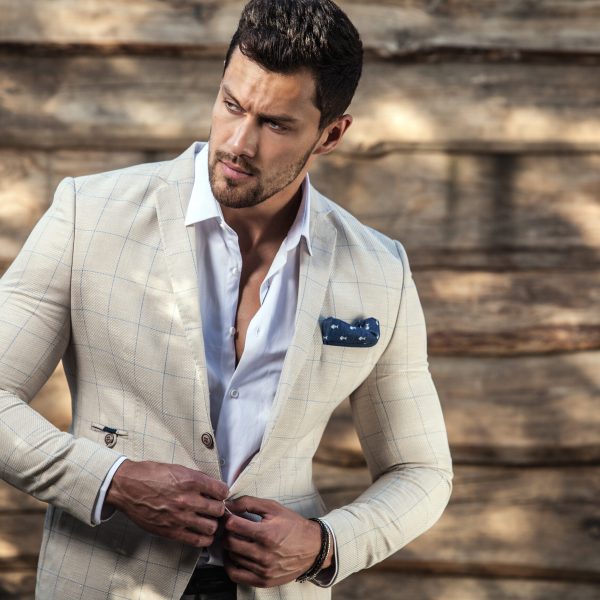Portrait of young beautiful fashionable man against wooden wall.