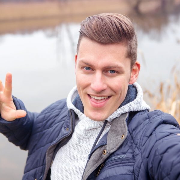 selfie of handsome blond man in front of lake in the cold