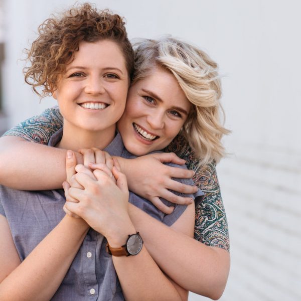 Portrait of a smiling young lesbian couple hugging each other while standing together on a city street