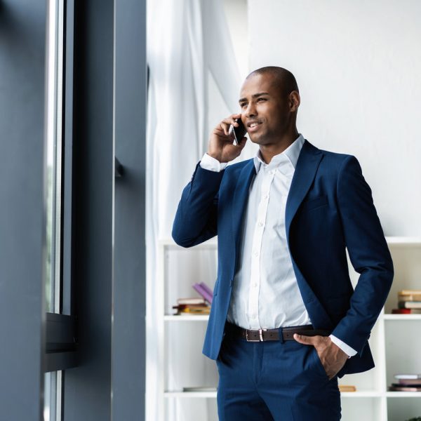 handsome african american businessman talking on mobile phone in modern office
