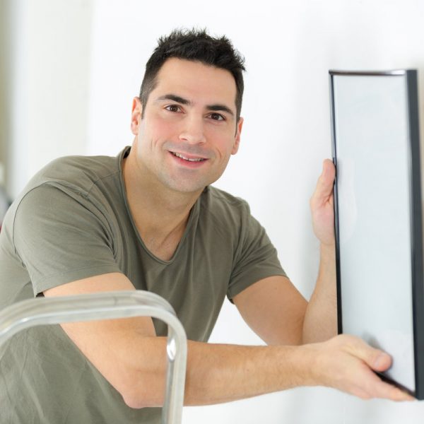 man hanging blank picture on wall
