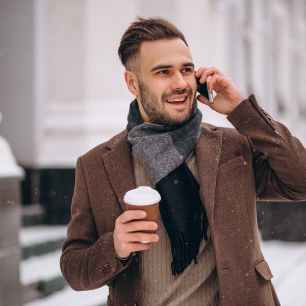 Young handsome man drinking coffee and talking on phone