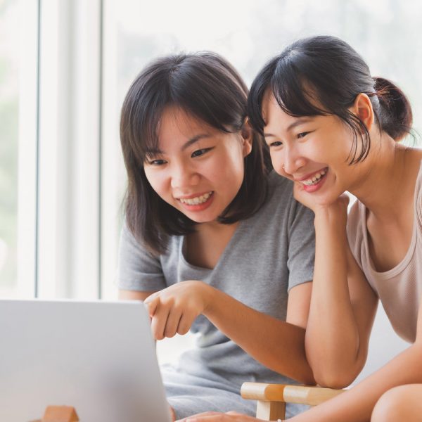 Young cheerful happy students working on laptop notebook together at coffee cafe.