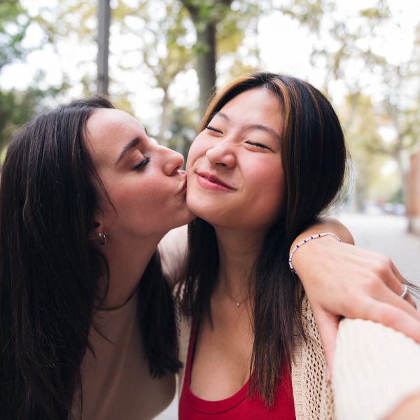 selfie of two young women kissing happy and having fun while they date, concept of friendship and love between people of the same sex