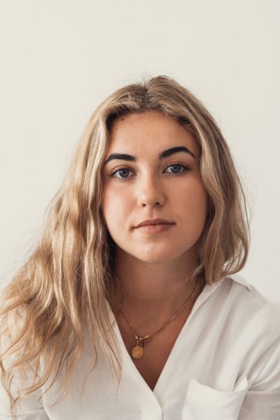 Positive serious millennial model girl home female head shot portrait. Beautiful young adult Caucasian woman looking at camera, posing in apartment. Front profile picture